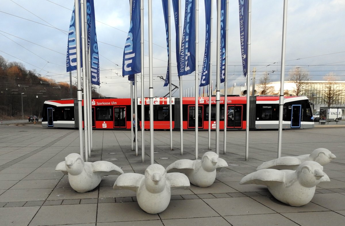 Avenio M Nr.53 fährt in die Haltestelle Donauhalle ein. Im Vordergrund stehen Ulmer Spatzen vor der Ulmer Messe am 01.03.2019.