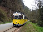 Triebwagen T 57 Nr.2 von VEB Gotha, Baujahr 1957 und Beiwagen B 2-62 von VEB Gotha, Baujahr 1963 fahren im Kirnitzschtal beim Stein des Nationalparks vorbei,am 11.04.2016.